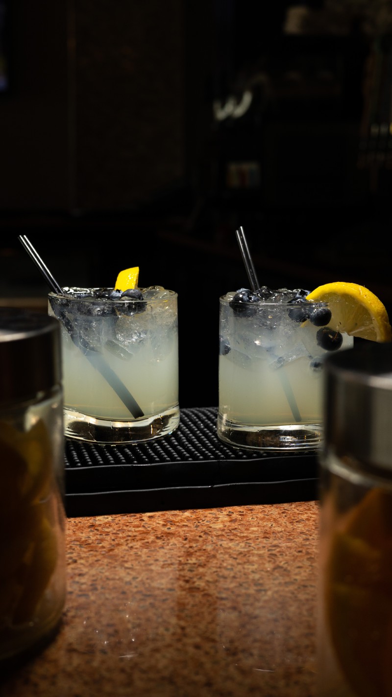 Two glasses of lemonade on a bar.