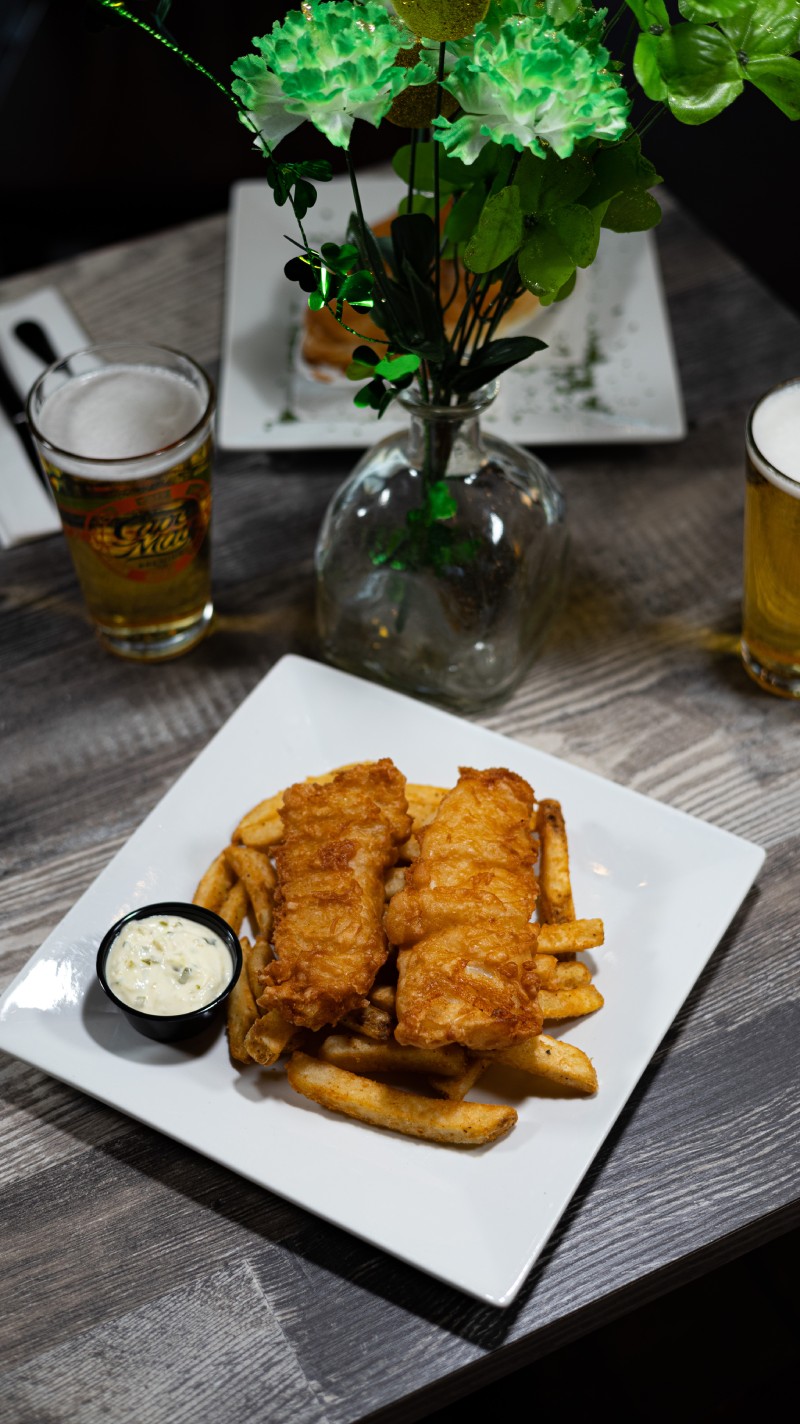 A plate of fish and chips and a glass of beer on a table.