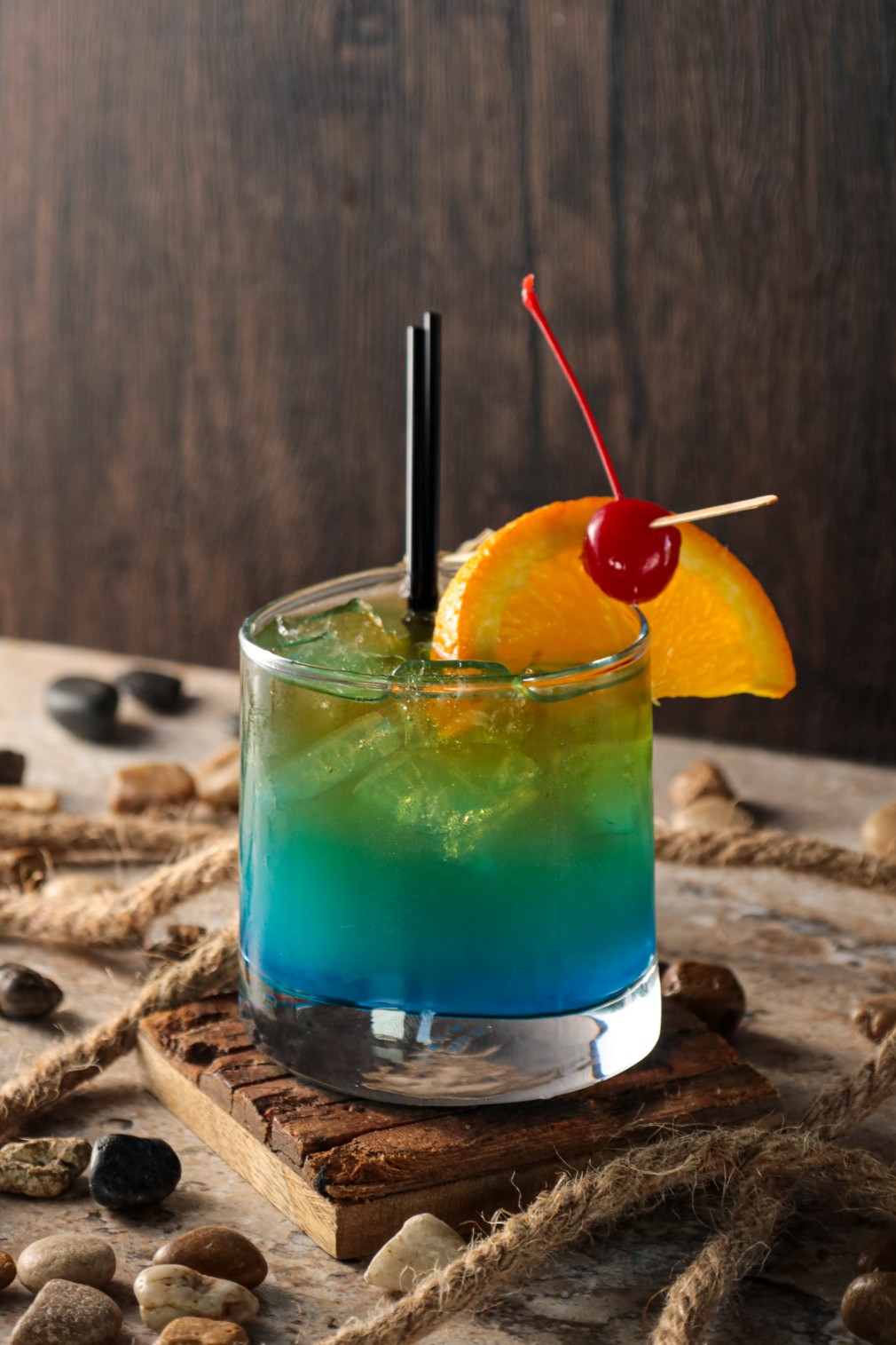 A blue cocktail with a cherry on top.