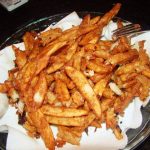 A plate of french fries with a fork.