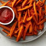 Sweet potato fries with ketchup on a plate.