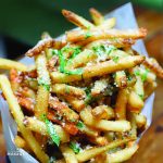 A bowl of french fries with parmesan and parsley.